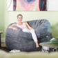 Woman relaxing on a large Graphite grey corduroy Shloomfy beanbag in a bright lounge