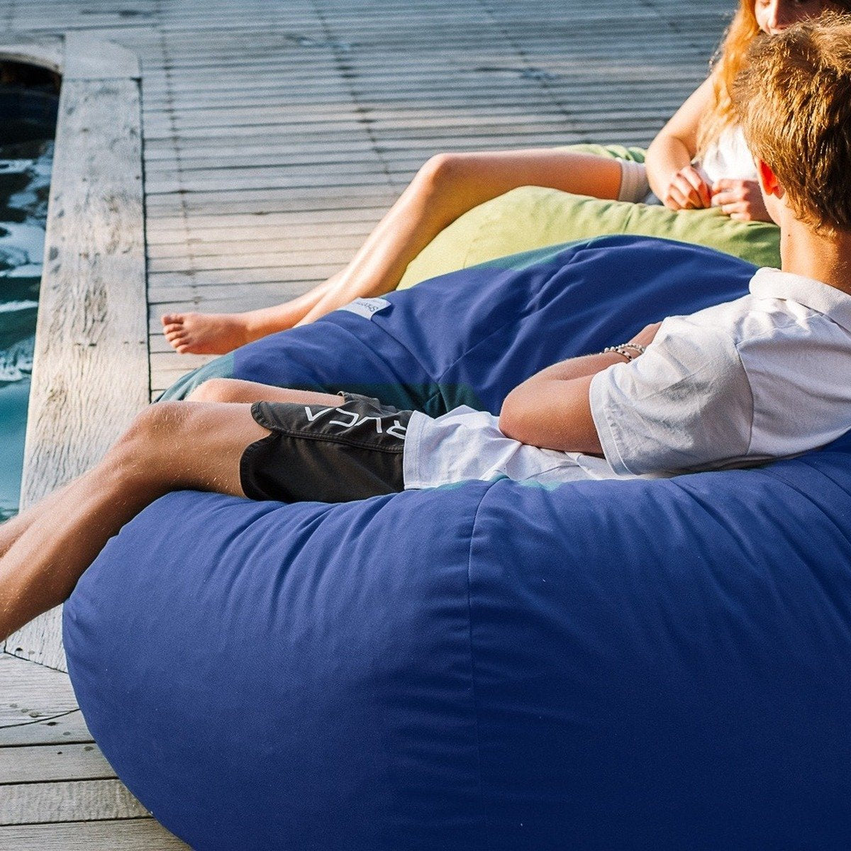 Navy Shloomfy patio beanbag beside a swimming pool