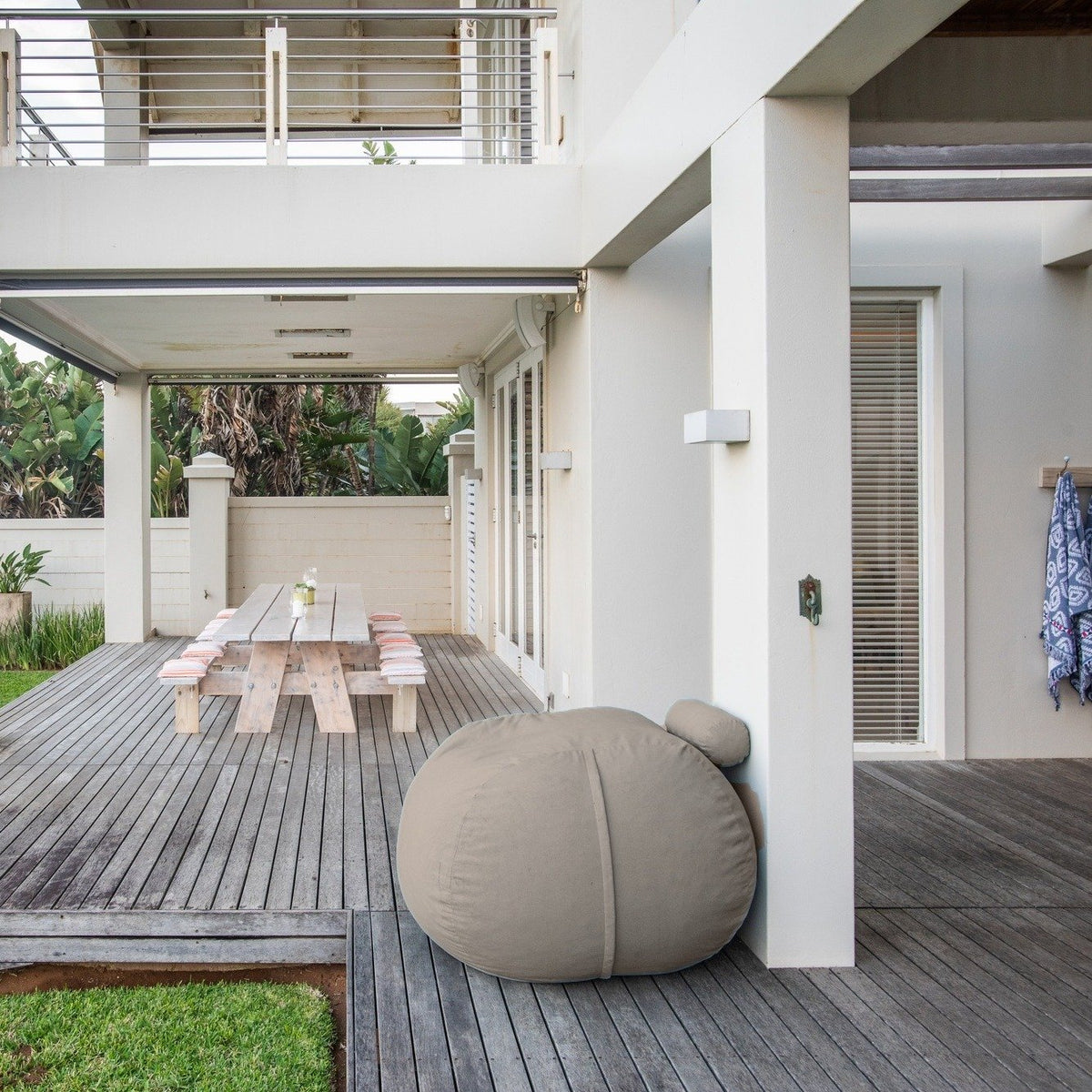 Putty Shloomfy patio beanbag on a wooden deck beside the lawn