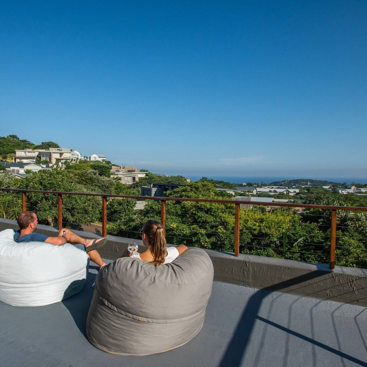 Putty and Off White Shloomfy patio beanbags on a rooftop with a sea view