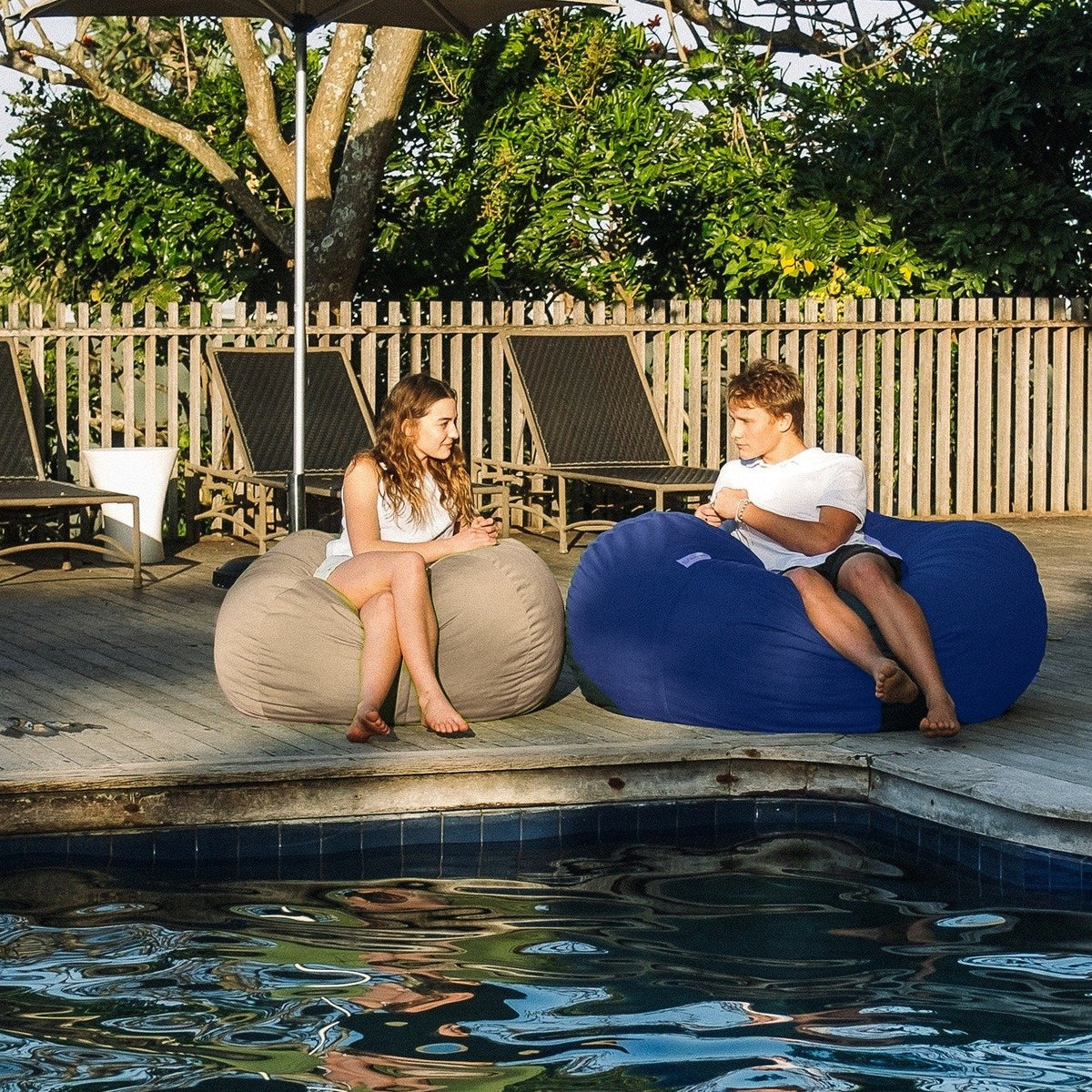 Sand and Navy Shloomfy patio beanbags on a pool deck